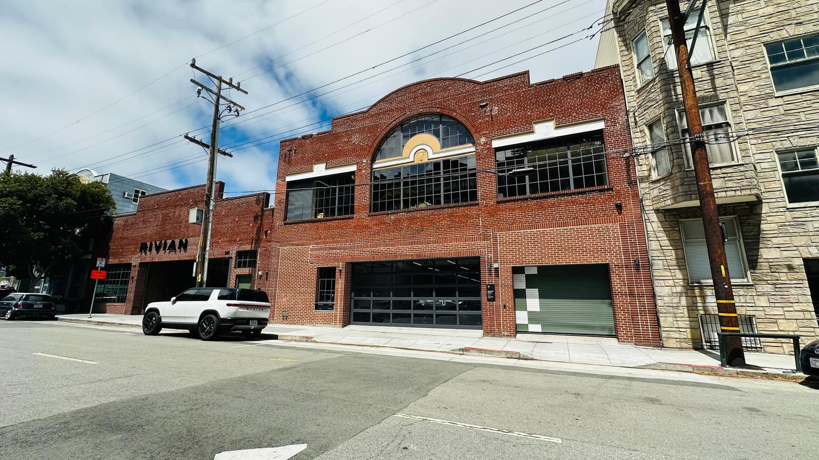 A brick warehouse with a large arched window in Hayes Valley, now occupied by a car showroom.