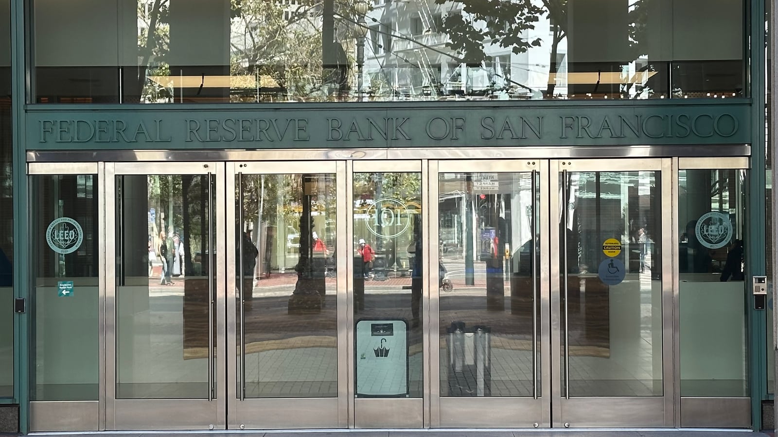 The Federal Reserve Bank of San Francisco entrance on Market Street, its carved name across the stone lintel above the glass doors.