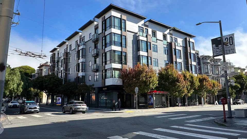 A new mid-rise apartment block on a Hayes Valley corner above ground-floor retail.