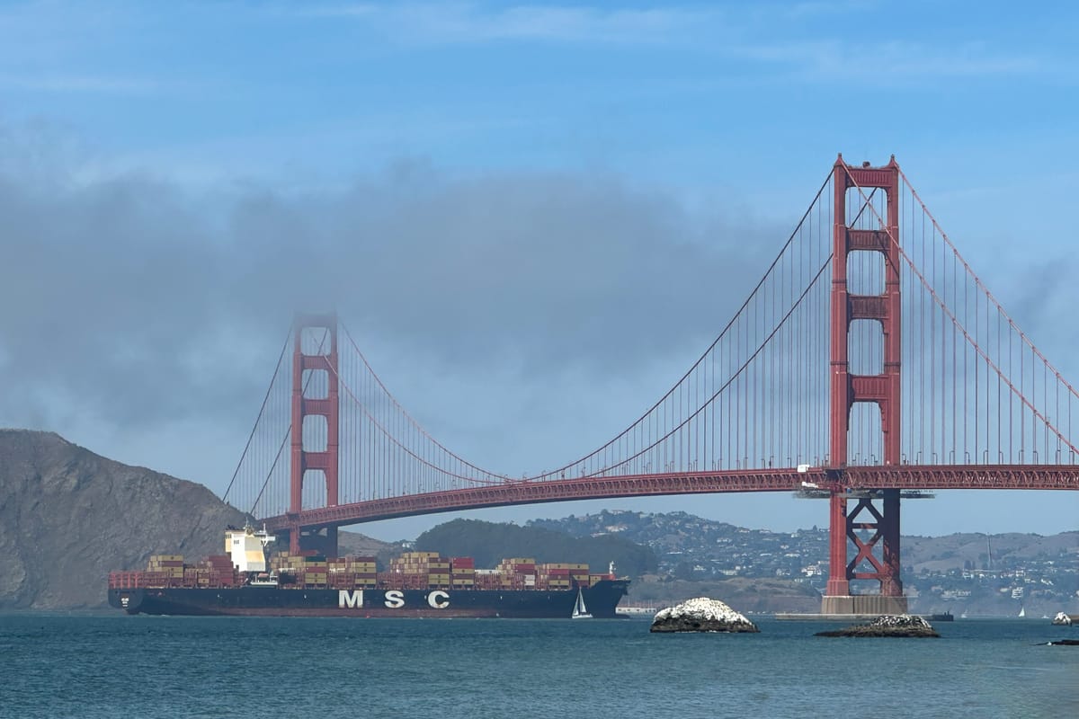 The Golden Gate Bridge seen from Baker Beach at the western edge of Sea Cliff, San Francisco, a container ship passing beneath and the Marin Headlands behind.